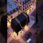 isometric scene of a luxury boutique shaped like a black quilted handbag with gold chain handle